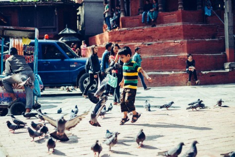 Kid running to pigeons in Kathmandu's Durbar Square, Nepal